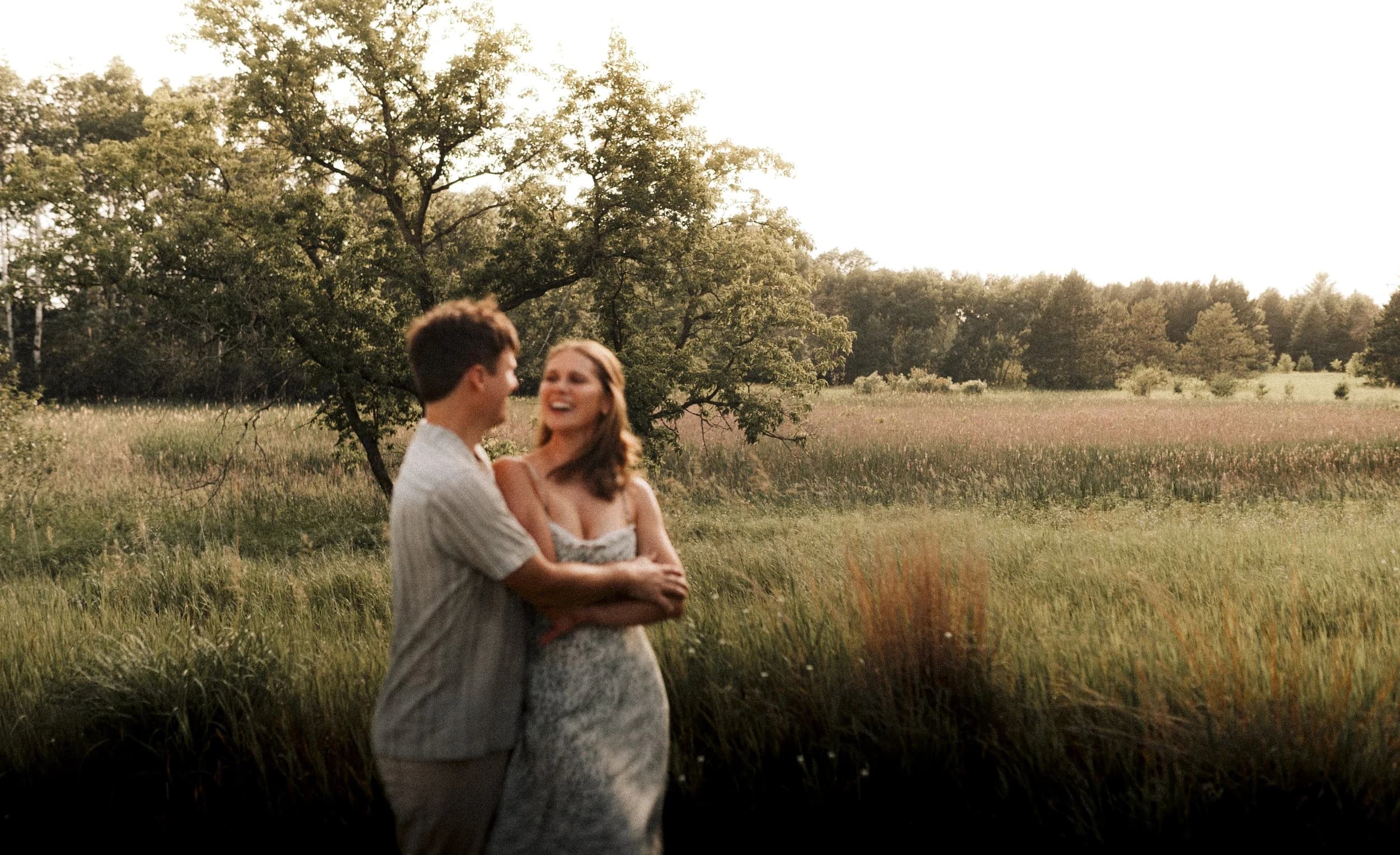 Couple walking through golden field at sunset